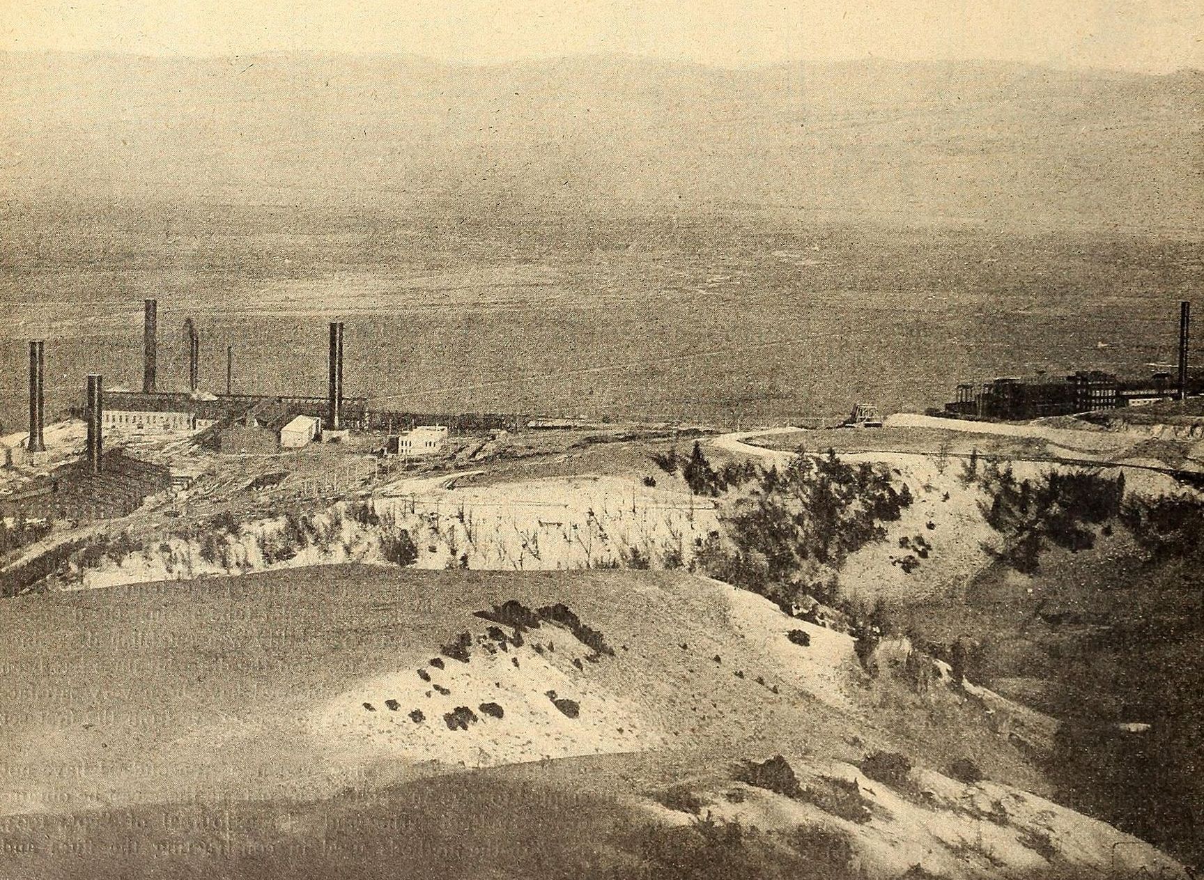 The Washoe Reduction Works spread along a hillside with several smokestacks, eroded slopes in the foreground, 1905