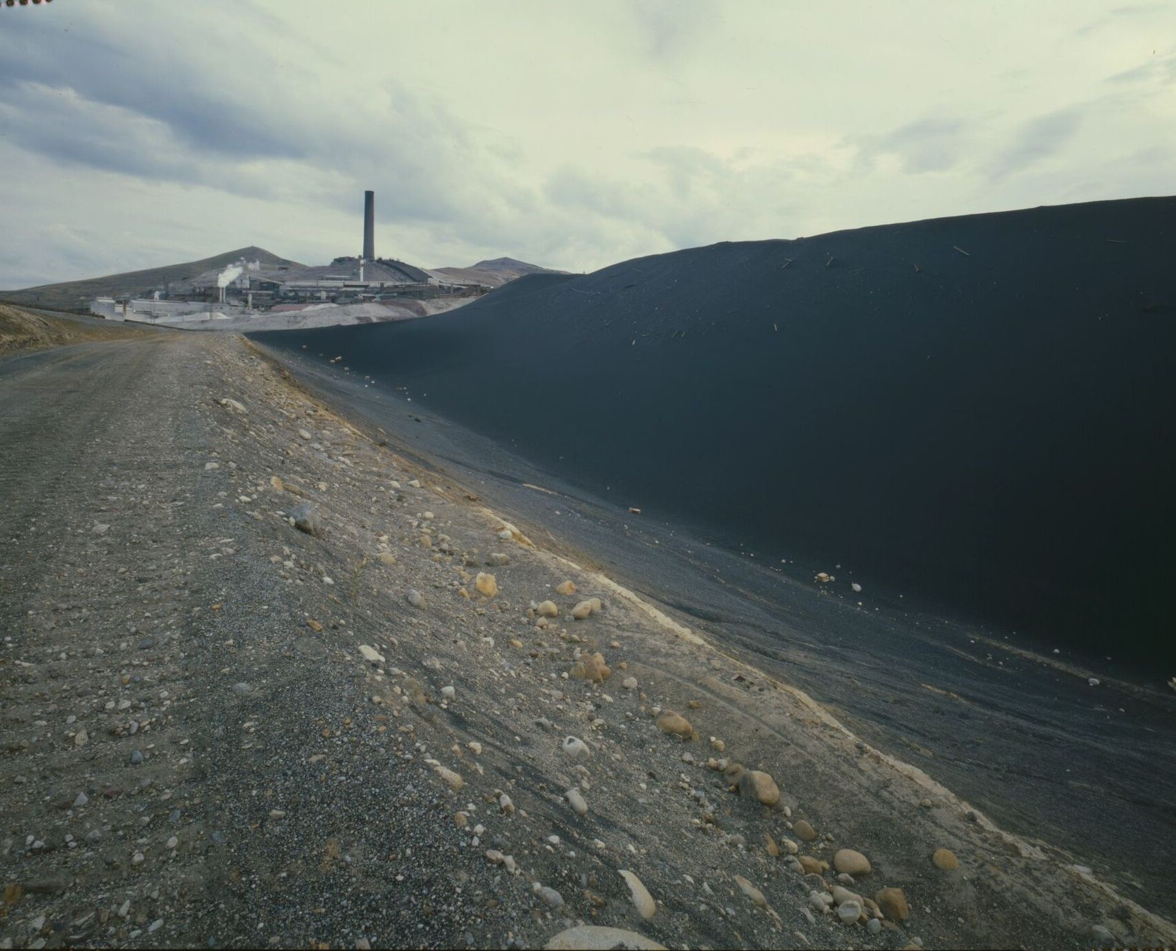 The Anaconda smelter stack on Smelter Hill, seen past a long black slag dump, in 1979