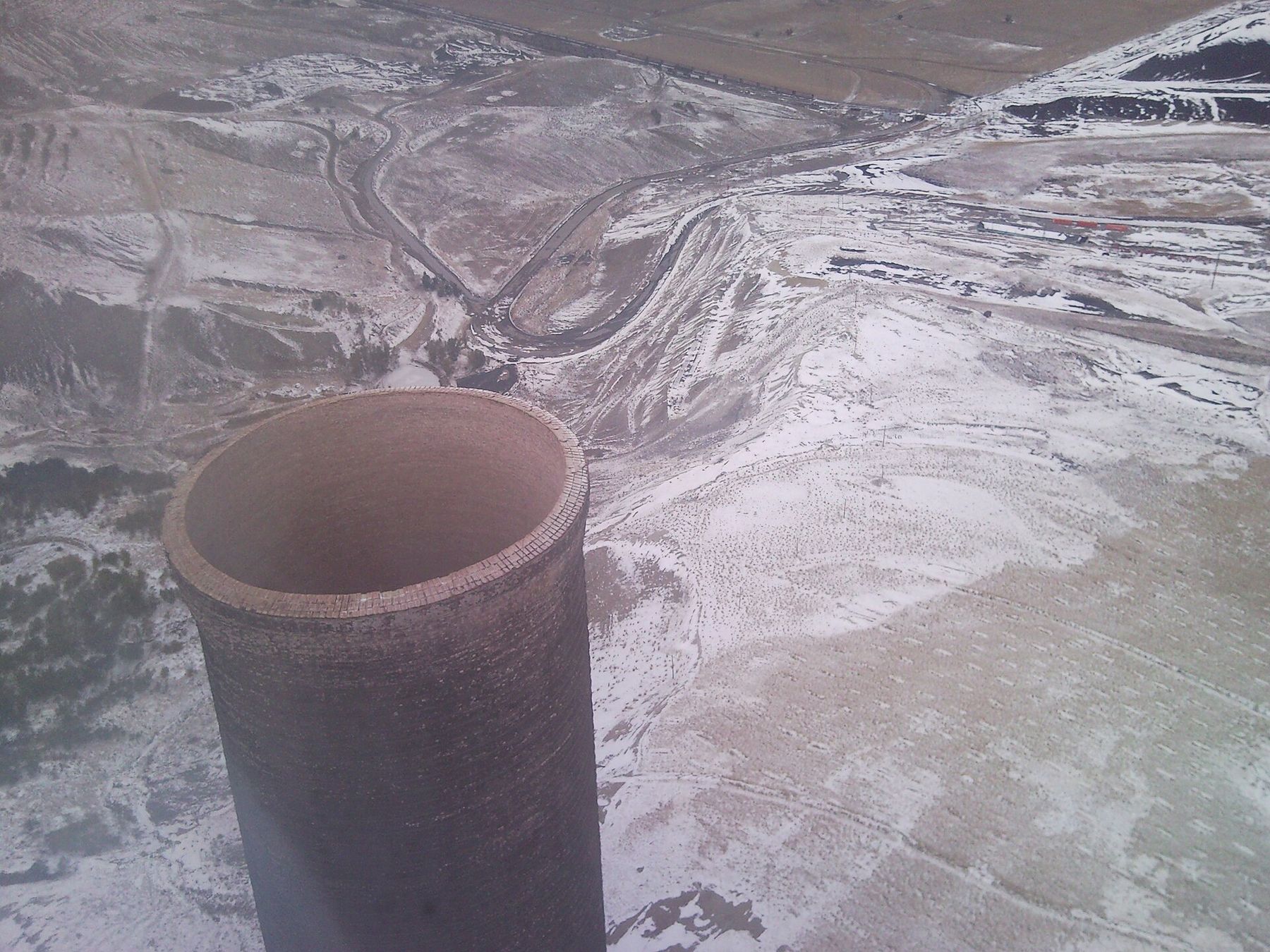 Looking straight down at the open brick crown of the stack, slag piles and roads far below